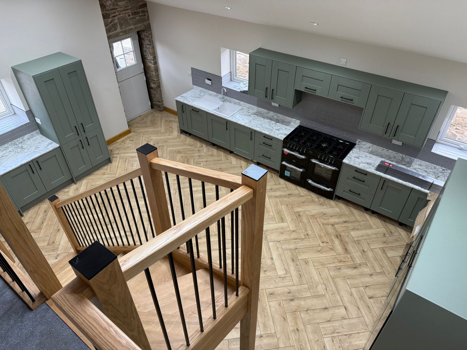 Green shaker kitchen and oak staircase in the finished Edenfield barn conversion
