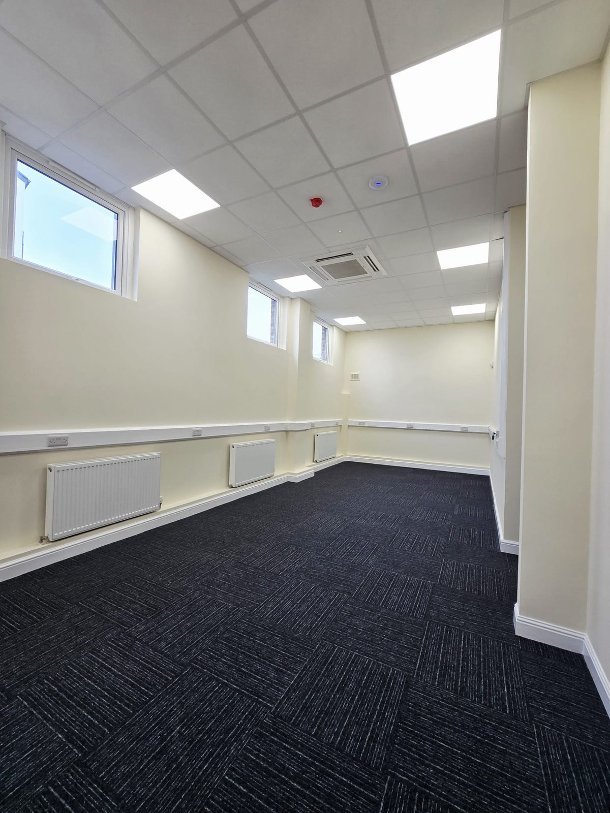 Refurbished open-plan office space with new carpet tiles and suspended ceiling in Rochdale